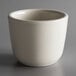 A Tuxton Reno eggshell white china tea cup on a gray surface.