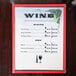 Menu paper with a grapevine and wine glass design on a table.