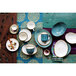A group of Tuxton Capistrano bowls on a table with a variety of dishes and cups.