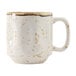 A white china mug with brown speckles and a white and brown handle.