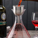 A Franmara stainless steel decanter funnel set with red wine being poured into a decanter.