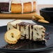 A slice of Pellman chocolate chip cheesecake with cookies on a black plate.
