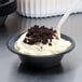 A bowl of Spring Glen Dirt Pudding with whipped cream and chocolate crumbles with a spoon.