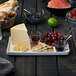 A table with a rectangular white porcelain platter of cheese, grapes, and crackers.