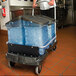 A man pushing a black Rubbermaid cart with a blue plastic container of ice.