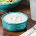 A Fiesta Turquoise china chowder bowl filled with white sauce next to a bowl of salad.