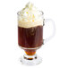An Arcoroc tempered glass Irish coffee mug filled with brown liquid and topped with whipped cream.