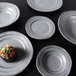A group of Elite Global Solutions Della Terra melamine stoneware irregular round bowls with food on them.