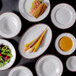 A group of Elite Global Solutions white crackle melamine plates with food on them.