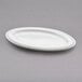A white oval melamine plate with a beaded rim.