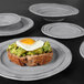 A close-up of Elite Global Solutions Della Terra irregular round serving bowl with food on it, including a fried egg on a piece of bread.