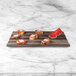 A faux hickory wood melamine serving board with slices of bread and watermelon on it.