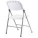 A white folding chair with silver legs.