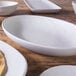 A close up of an off white Elite Global Solutions Tenaya deep oval melamine plate.