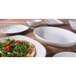 An Elite Global Solutions off white melamine plate with food and a white bowl on a wood surface.