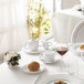 A white table set with Chef & Sommelier white bone china creamers, plates, and glasses of wine.