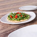 An Elite Global Solutions off white square melamine plate with a salad on it on a table.