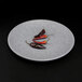 A round gray Elite Global Solutions melamine plate with red and black chili peppers on it.