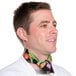 A man wearing a white neckerchief with a colorful vegetable pattern around his neck.