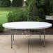 A white Lancaster Table & Seating folding table on a concrete surface.