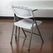 A white Lancaster Table & Seating plastic folding table with a white plastic folding chair on top.