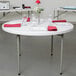 A white Lancaster Table & Seating folding table with white plates and glasses on it.