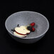 A white Elite Global Solutions round melamine serving bowl filled with fruit and cheese.