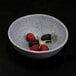 A Tenaya granite stone melamine bowl filled with raspberries on a black surface.