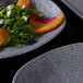 A plate of salad with peach slices on it served on an Elite Global Solutions granite stone square melamine plate.