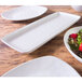 A bowl of salad with strawberries and nuts on a white Elite Global Solutions rectangular melamine plate.