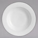 A Chef & Sommelier white bone china bowl with a white rim on a gray surface.