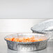 A group of round Durable Packaging foil pans with food in them.