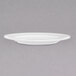 A Chef & Sommelier white bone china dinner plate with a rim on a gray surface.