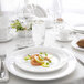 A white table setting with a Chef & Sommelier white bone china dinner plate of food and a close-up of a knife.