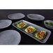 A set of Elite Global Solutions round granite stone melamine plates on a table with food.
