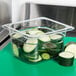 A Carlisle clear plastic food pan filled with cucumber slices.