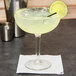 A Libbey Fiesta Grande Margarita glass filled with a drink and a lime slice on the rim.