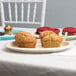 An ivory oval paper platter holding muffins on a table.
