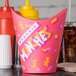 A pink Solo paper container with a design on it next to condiments and a yellow bottle with a pointy tip.