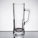 An Arcoroc clear glass beer mug with a handle on a table.