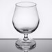 An Arcoroc tulip beer glass with a clear liquid inside it on a reflective surface.