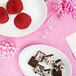 A plate of brownies, chocolate covered strawberries, and a piece of cake on a table with a candy pink table cover.