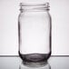 An Arcoroc clear glass drinking jar with a lid on a table.