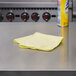 A yellow Rubbermaid HYGEN microfiber cloth on a stainless steel counter.