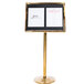 A brass Aarco pedestal sign board on a counter with black and white signs.