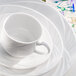 An Arcoroc white porcelain coffee cup on a saucer.