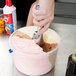 A hand using a Zeroll ice cream scoop to scoop ice cream.