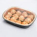 A Durable Packaging black and gold aluminum foil pan with food in a plastic container.