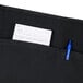 A Chef Revival black poly-cotton waist apron with a piece of paper in a pocket.