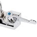 A close-up of an Equip by T&S wall mount swivel faucet with wrist action handles and blue and chrome levers.
